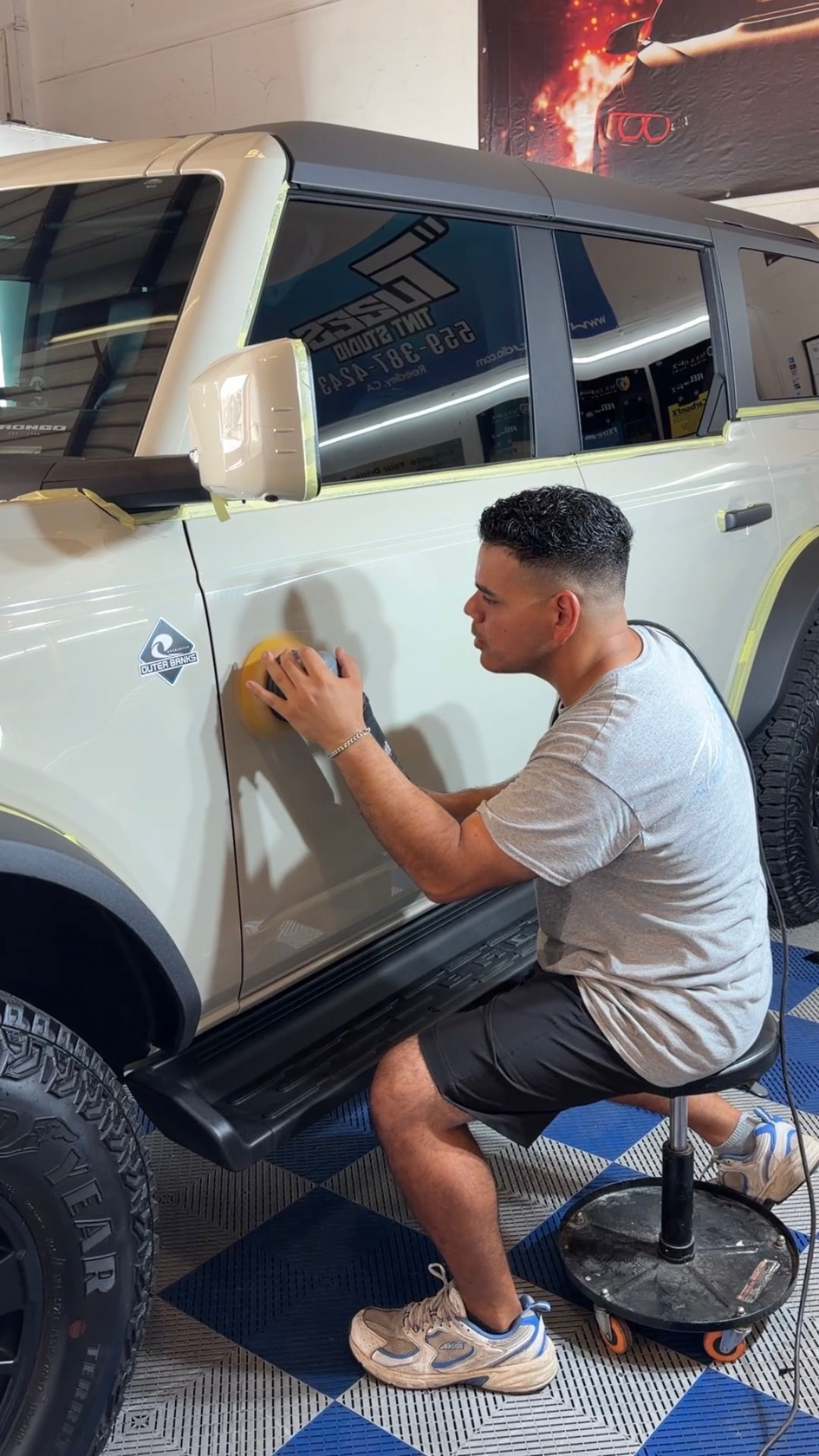 Detailer machine polishing a white Ford Bronco door panel to remove swirls and restore gloss