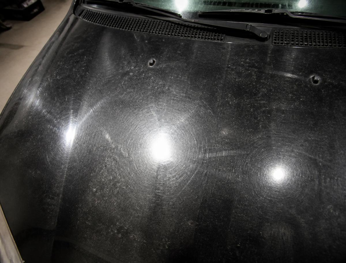 Black car hood covered in swirl marks and oxidation